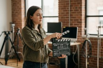 Étudiante en cinéma tenant un clap de tournage dans un studio de formation audiovisuelle